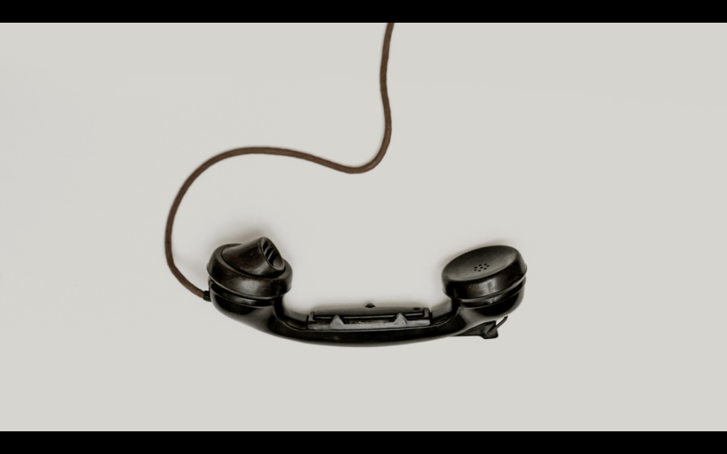 The handset of a rotary phone hanging down